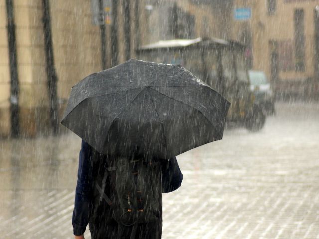 雨の中で傘を差している人の画像